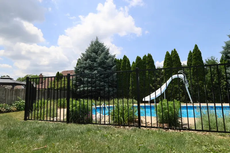 Black aluminum fence around an in-ground pool with a slide