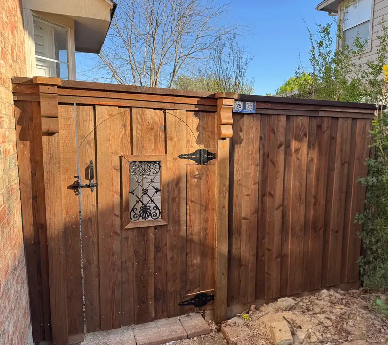 Stained wood privacy gate with a decorative iron window and corbels